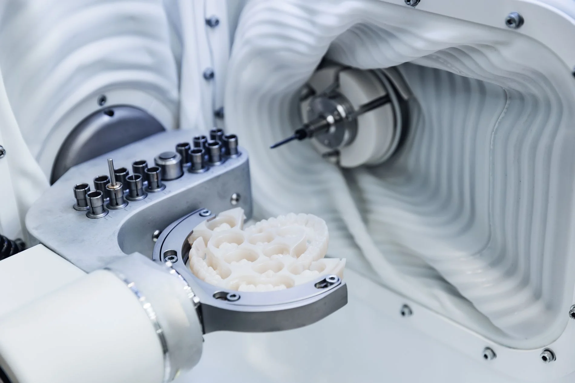 Eine Nahaufnahme einer CAD/CAM Dentalfräse, die in einem Labor ein künstliches Gebiss formt.